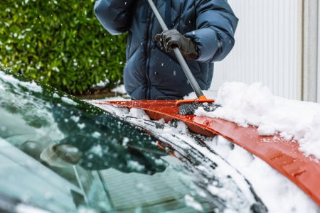 Photo for Cleaning snow from windshield. Cleaning and clearing the car from snow on a winter day. - Royalty Free Image