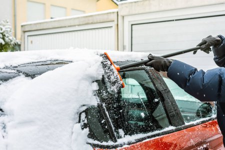 Foto de Limpiando nieve del parabrisas. Limpieza y limpieza del coche de la nieve en un día de invierno. - Imagen libre de derechos
