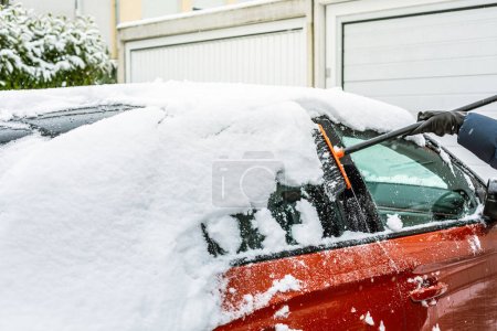 Foto de Limpiando nieve del parabrisas. Limpieza y limpieza del coche de la nieve en un día de invierno. - Imagen libre de derechos