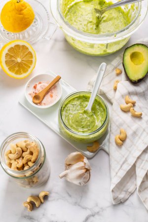 Homemade avocado yogurt dressing with ingredients on kitchen table