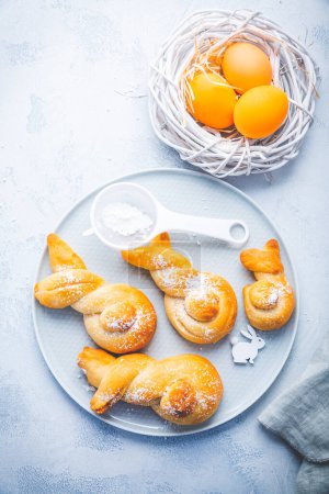 Photo for Buns made from yeast dough in a shape of Easter bunny and colored eggs - Royalty Free Image
