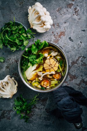 Foto de Caldo de ternera y ajo miso, sopa con verduras, champiñones y cilantro en una olla - Imagen libre de derechos