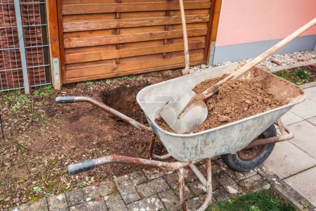 Téléchargez les photos : Brouette avec terre et pelle, creuser un trou pour planter un arbre ou une construction - en image libre de droit