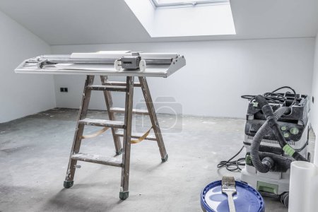 Foto de Renovación del hogar - habitación vacía con mesa de pegar para cortar papel pintado y herramientas - Imagen libre de derechos