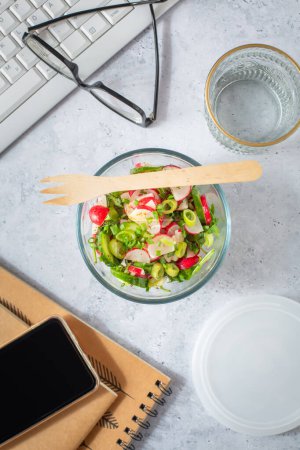 Téléchargez les photos : Aliments sains dans un bureau. Salade de radis et concombre préparée sur un bureau avec fournitures de bureau - en image libre de droit