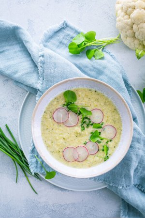 Foto de Sopa de coliflor blanca cremosa con rábano y cebollino, comida saludable con hierbas - Imagen libre de derechos