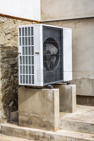 Air source heat pump installed outside of old renovated house, green renewable energy concept of heat pump