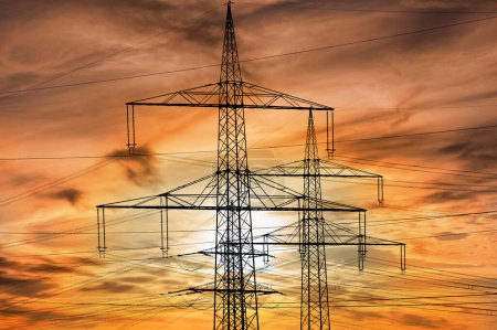 high voltage and electric pylons against sky with clouds