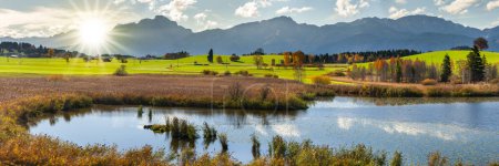 Photo for Panoramic landscape with lake aund mountainrange against sky with sun - Royalty Free Image