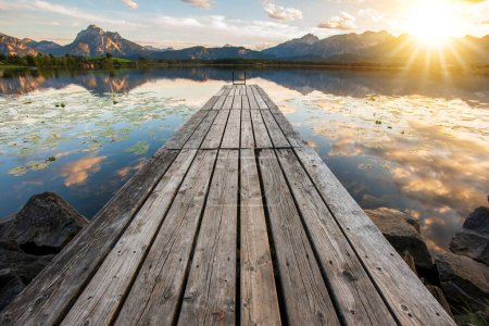 Téléchargez les photos : Jetée et jetée en bois sur le lac avec chaîne de montagnes au coucher du soleil - en image libre de droit