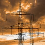 high voltage pylons for electricity and power against sky with dramatic clouds