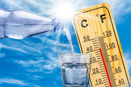 Photo for Thermometer shows high temperature in summer heat and bottle with water with drinking glass - Royalty Free Image