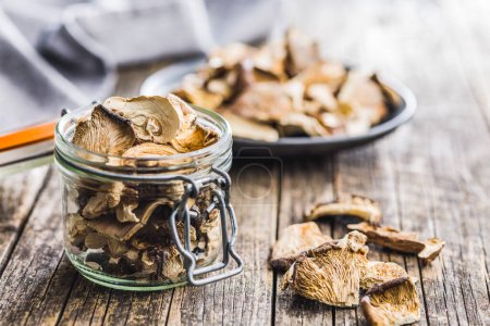 Sliced dried mushrooms in jar on the wooden table.