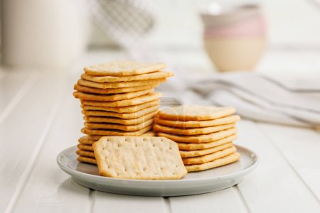 A plate filled with crackers sitting on a white table.