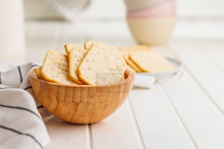 A bowl filled with crackers sitting on a white table.
