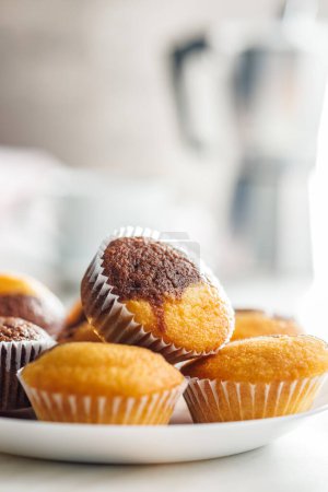 Une variété de muffins brun doré sur une table blanche, invitant au goût.