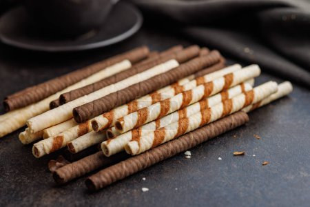 Assorted Chocolate and Vanilla Cream Filled Wafer rolls on a dark table.