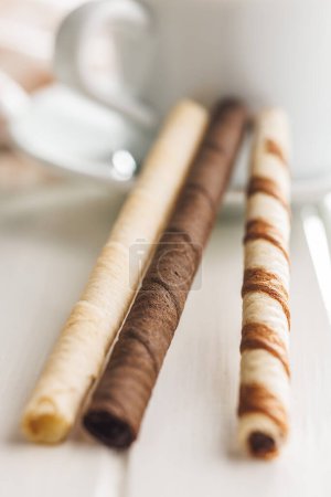 Surtido de chocolate y crema de vainilla rellenos rollos de oblea en una mesa blanca.