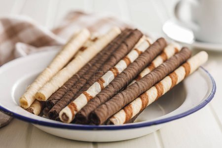 Surtido de chocolate y crema de vainilla rellenos rollos de oblea en el plato en una mesa blanca.