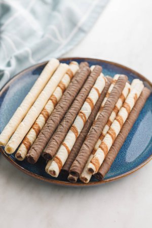 Assorted Chocolate and Vanilla Cream Filled Wafer rolls on plate on a white table.