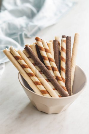 Assorted Chocolate and Vanilla Cream Filled Wafer rolls in bowl on a white table.