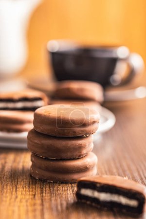 Vue rapprochée des biscuits sandwich enrobés de chocolat sur une table en bois.