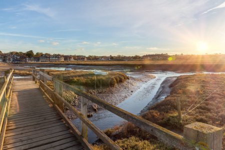 Photo for Blakeney quay wooden foot bridge in Norfolk UK at sunset. Low tide creek and water outlet to the sea - Royalty Free Image