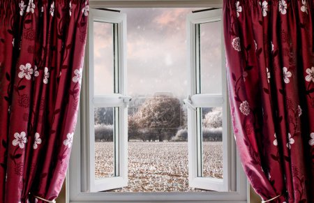 Foto de Ventana abierta con hermosa vista al paisaje rural de invierno. Cortinas rojas y ventanas de doble acristalamiento estilo de vida moderno - Imagen libre de derechos