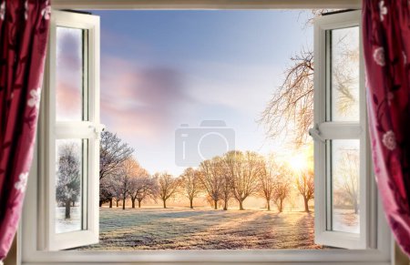 Téléchargez les photos : Ouvrez la fenêtre donnant sur le lever du soleil givré à travers les arbres et les champs en hiver. Beau ciel et nuages - en image libre de droit
