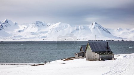 Abandoned miners cabins at Camp Mansfield, Svalbard, and panoramic view of the Kongsfjorden and surrounding mountains.