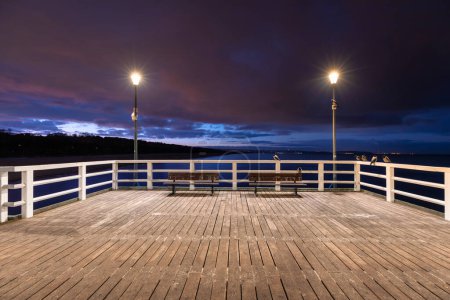 Photo for Illuminated pier in Brzezno on the winter beach at dusk, Gdansk.  Poland. - Royalty Free Image