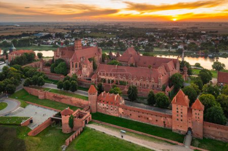 Téléchargez les photos : Le Château de l'Ordre Teutonique à Malbork au bord de la rivière Nogat au coucher du soleil. Pologne - en image libre de droit