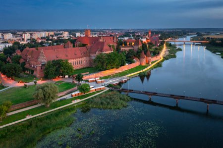 Foto de El Castillo de la Orden Teutónica en Malbork junto al río Nogat al atardecer. Polonia - Imagen libre de derechos