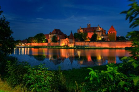 Téléchargez les photos : Le Château de l'Ordre Teutonique à Malbork au bord de la rivière Nogat au crépuscule. Pologne - en image libre de droit