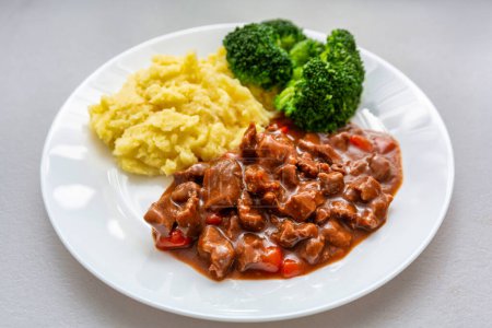 Photo for Beef stew on a plate with boiled potatoes and green broccoli - Royalty Free Image