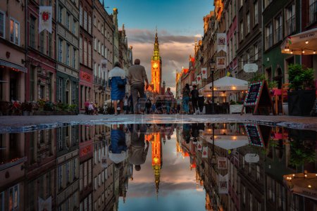 Téléchargez les photos : Gdansk, Pologne - 4 juillet 2022 : Les gens marchent sur la belle vieille ville de Gdansk avec l'hôtel de ville historique reflété dans l'eau, Pologne. - en image libre de droit