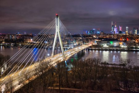 Foto de Puente Swietokrzyski sobre el río Vístula con una vista panorámica del centro de Varsovia por la noche. Polonia - Imagen libre de derechos