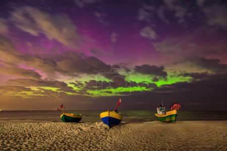 Northern lights over the Baltic Sea on the beach in Jantar with fishing boats, Poland.