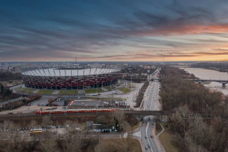 Foto de Warszawa, Polonia - 27 de enero de 2024: El Estadio Nacional de Varsovia iluminado en los colores nacionales de Polonia al atardecer. - Imagen libre de derechos