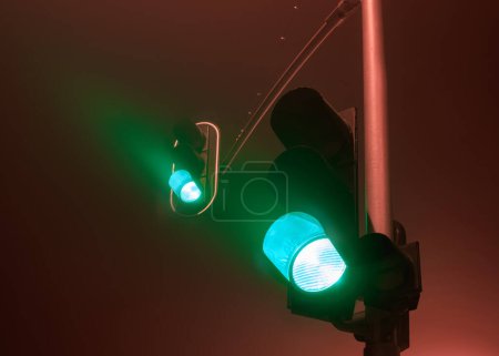Traffic lights with green light during a foggy night.