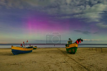 Téléchargez les photos : Aurores boréales sur la plage de la mer Baltique à Jantar avec bateaux de pêche, Pologne. - en image libre de droit