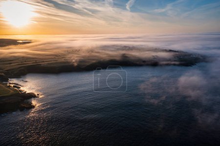 Nebliger Sonnenaufgang über der felsigen Küste von Kilkee, Grafschaft Clare. Irland