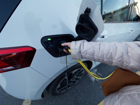Foto de Female silhouette charging a electric car, photo from below - Imagen libre de derechos