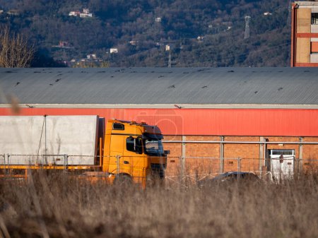 Camión semirremolque grande naranja industrial cargado con cabina larga para el descanso del conductor del camión que transporta la carga comercial en el semirremolque seco de la furgoneta que funciona