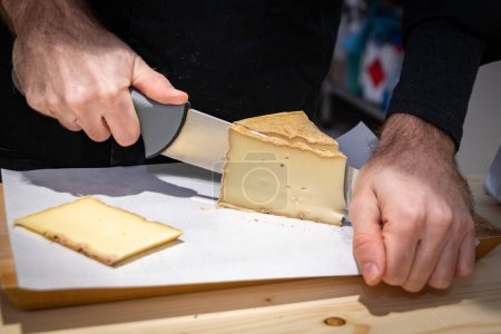 Téléchargez les photos : 11 juillet 2022, Lyon, France : Un homme coupe une portion du Vacherin Fribourgeois avec un fil de fer, un célèbre fromage suisse - en image libre de droit