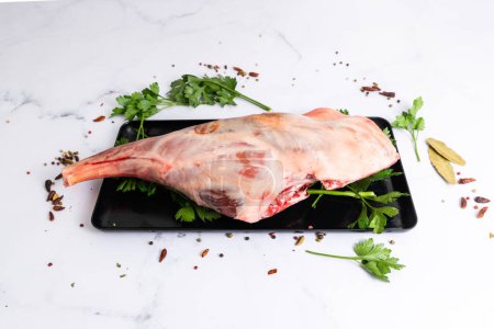 Téléchargez les photos : Epaule d'agneau crue prête pour la cuisson à l'ail, romarin. Fond noir. Vue du dessus - en image libre de droit