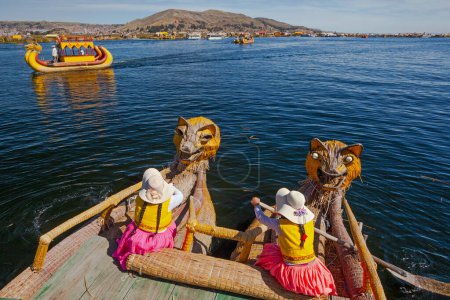 Photo for Uros, Peru - April 29, 2022: woman in traditional clothes rowing a uros totora boat near Uros Islands on Lake Titicaca in Peru. - Royalty Free Image