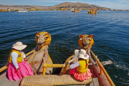 Photo for Uros, Peru - April 29, 2022: woman in traditional clothes rowing a uros totora boat near Uros Islands on Lake Titicaca in Peru. - Royalty Free Image