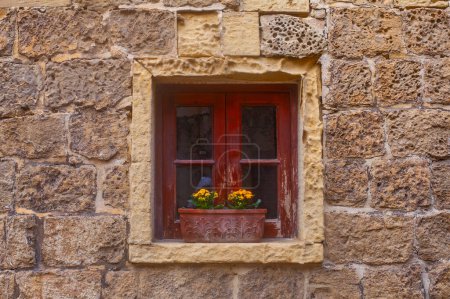 window with flowerpots on the Narrow street of ancient city Rabat with traditional maltese houses built of limestone, Victoria, Malta