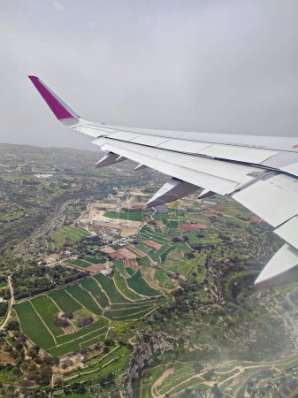 Clouds and a wing of Wizzair airbus from the airplane window. over Malta towns 